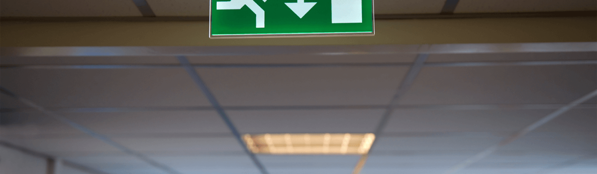 Emergency exit sign hanging from a ceiling
